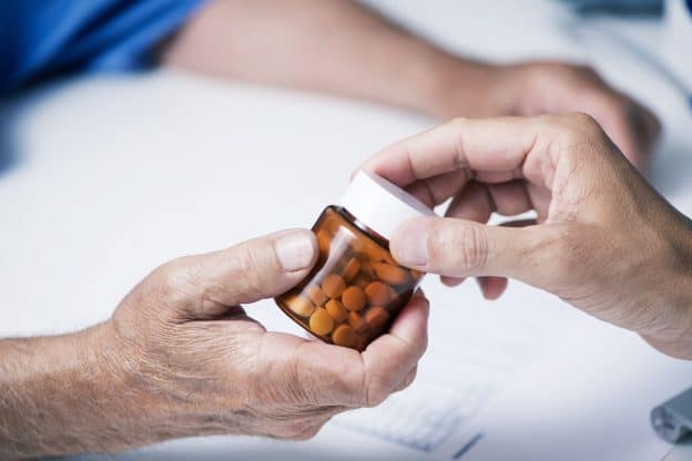Pharmacist hands a customer a bottle of prescription medications. Factor V Leiden may require daily medication.