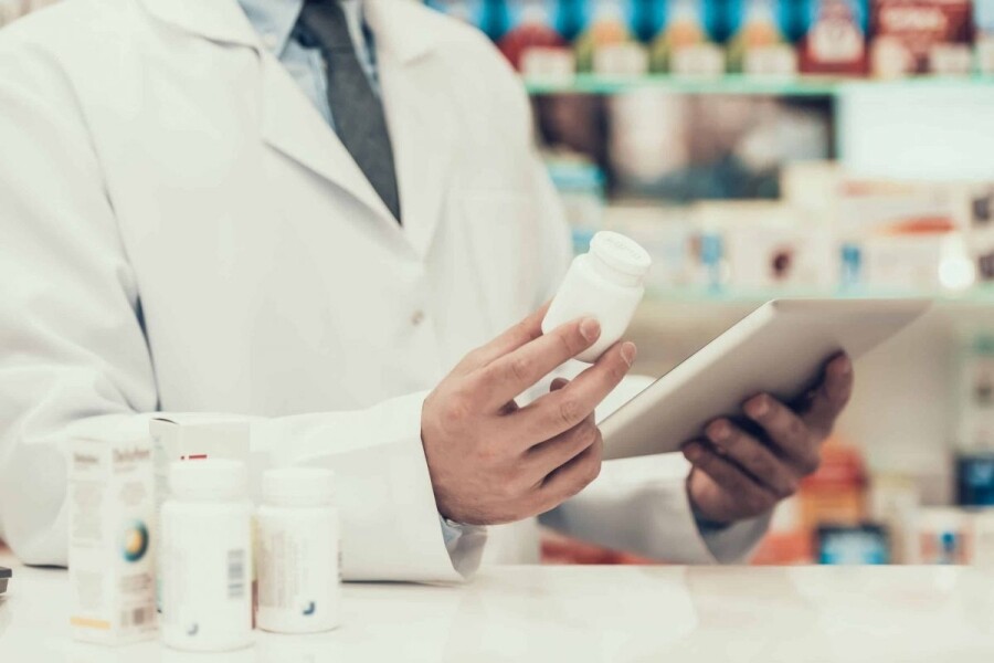 Closeup of a Pharmacist Holding Pills Bottle and Tablet.