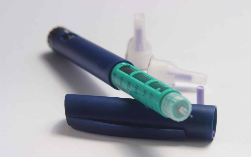 146686224 - close up photo, blue and green insulin pen at white background